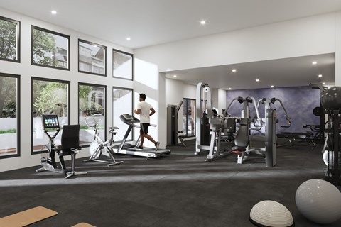 A man is working out on a treadmill in a spacious gym with various exercise equipment.