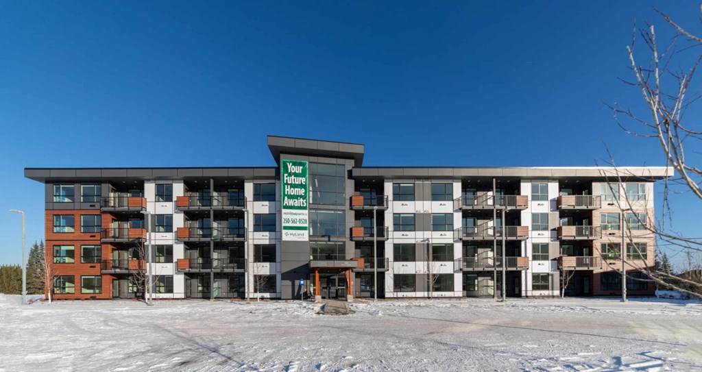 A large building with a sign that says "Your Home Awaits" in front of it.