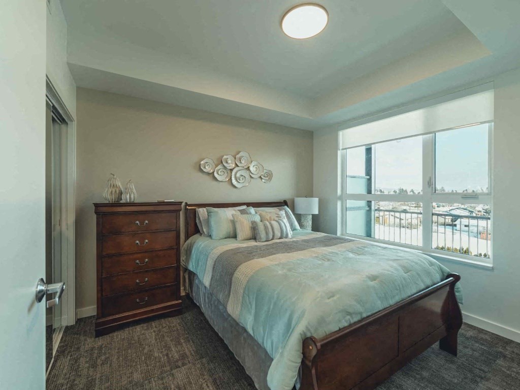 A bedroom with a large bed and a dresser with a mirror above it.