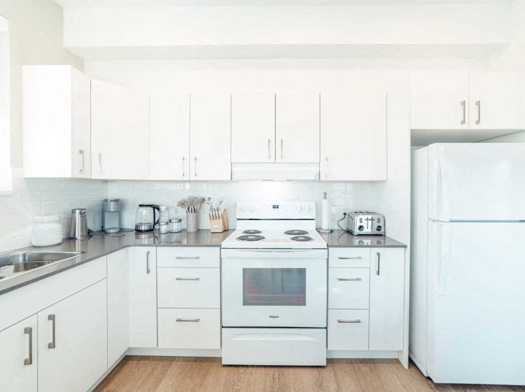 A white kitchen with a refrigerator on the right.