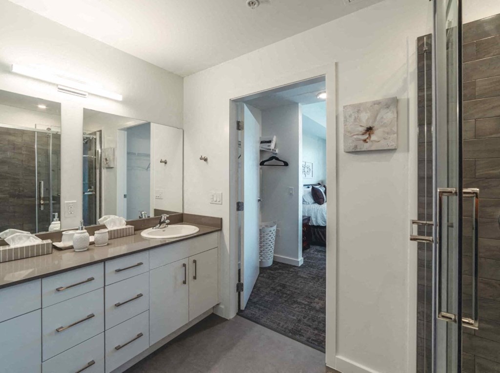 A bathroom with a double sink vanity and a mirror above it.