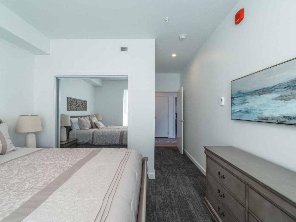 A bedroom with a large bed and a painting on the wall.