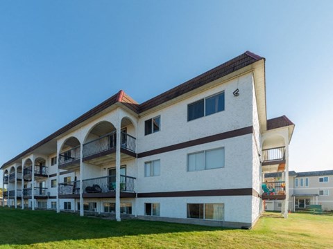 A white and brown building with balconies and a red roof.