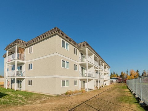 A large beige apartment building with multiple balconies and windows.