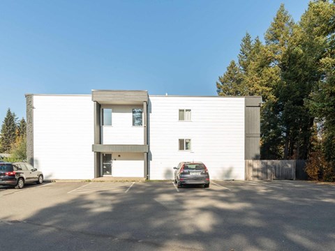 A modern white building with a car parked in front.