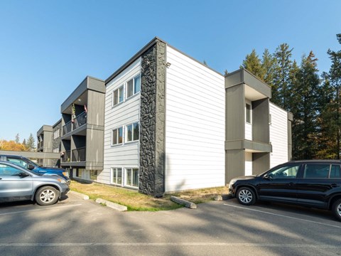 A modern two-story building with a parking lot in front.