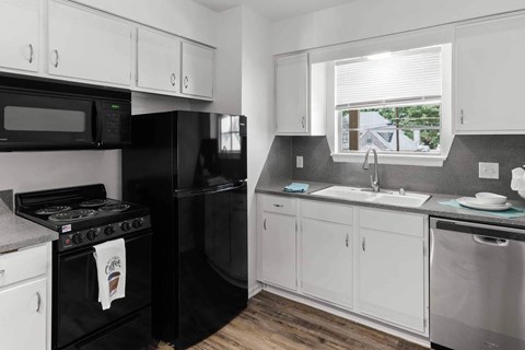 A black stove and refrigerator in a kitchen with white cabinets.