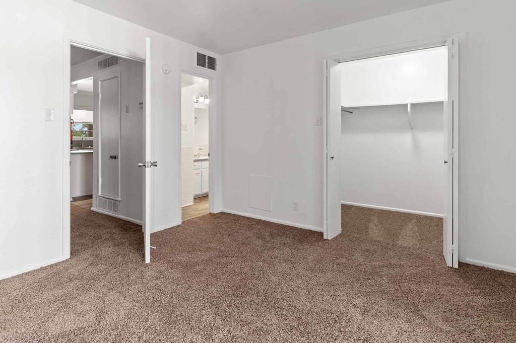 A white room with a carpeted floor and a doorway leading to another room.
