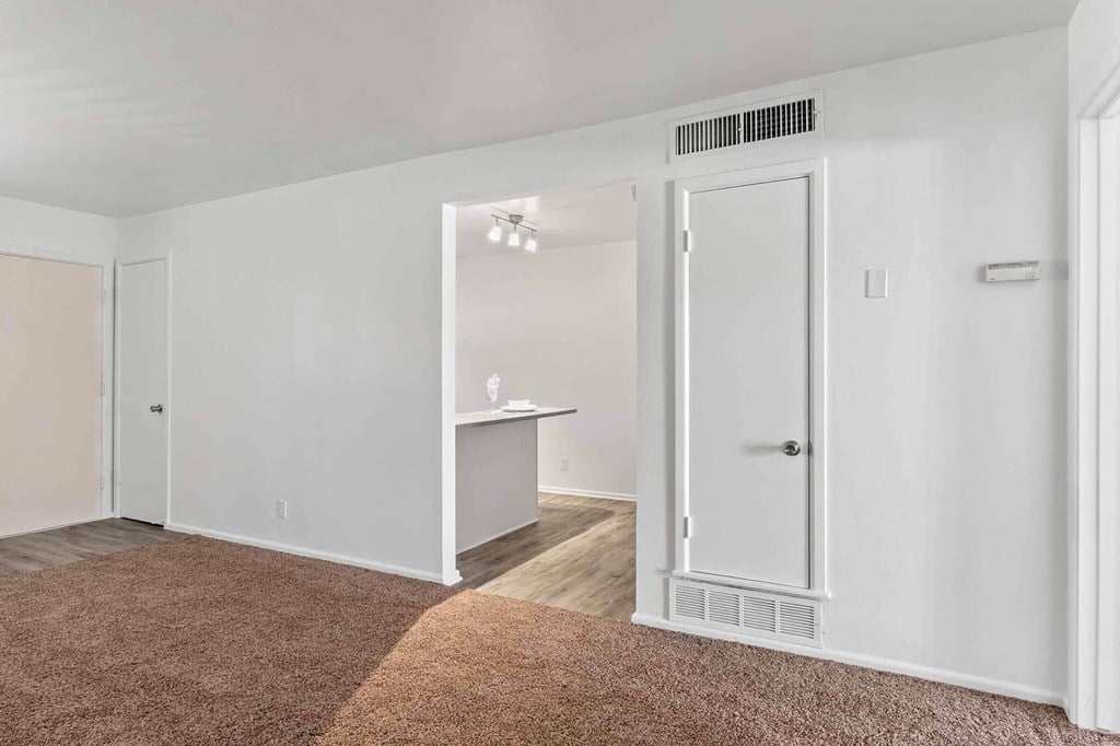 A white room with a brown carpet and a door on the right.