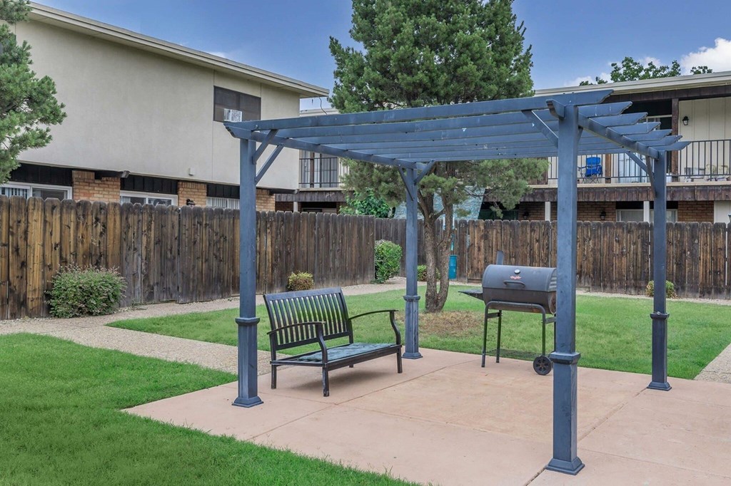 A patio with a bench and a grill under a canopy.