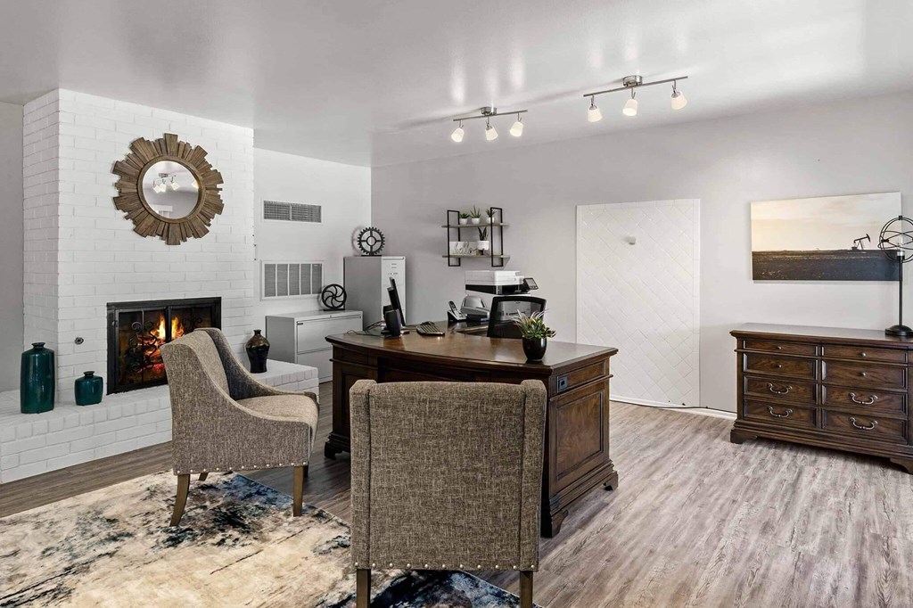 A room with a fireplace, a desk, and chairs.