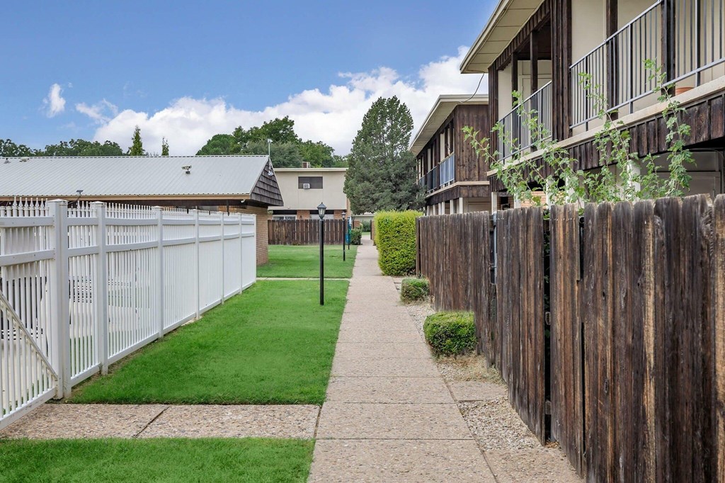 A white fence runs along the side of a building.