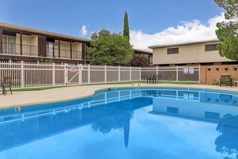 A swimming pool in front of a building with a fence around it.
