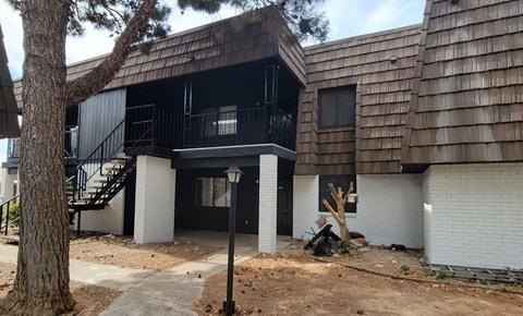 A black and white building with a tree in front.