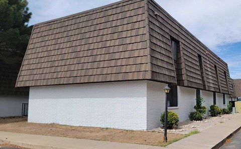 A white house with a brown roof and a black lamp post.
