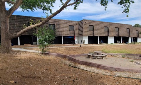 A building with a brown roof and a tree in front of it.