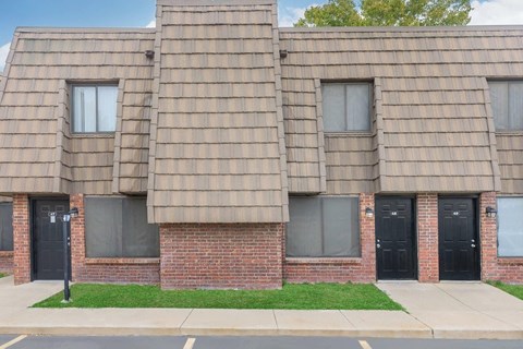 A building with a brown shingled roof and black doors.