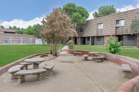 A courtyard with a tree and benches in front of a building.