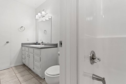 A white bathroom with a toilet, sink, and mirror.