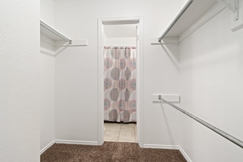 A white hallway with a brown carpet and a doorway leading to a bathroom.