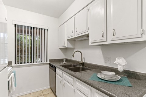 A kitchen with white cabinets and a granite countertop.