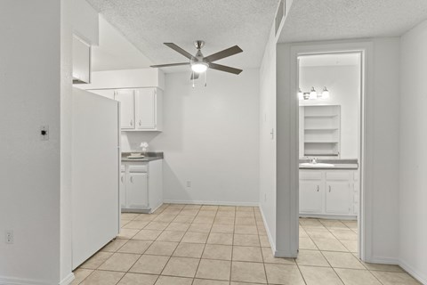 A white kitchen with a fan on the ceiling.