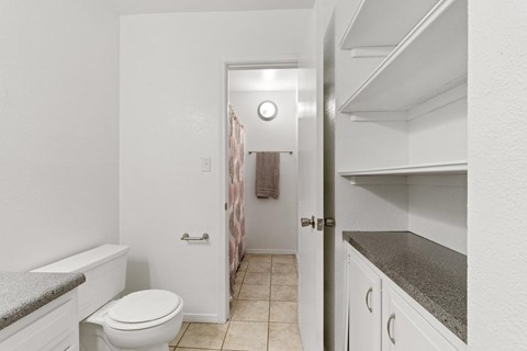 A white toilet sits in a small bathroom next to a white bathtub.