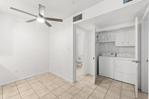 A white room with a fan and a bathroom with a toilet and sink.