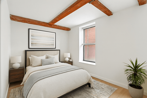 A bedroom with a large bed and a potted plant.