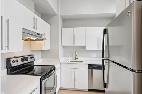A modern kitchen with white cabinets and stainless steel appliances.