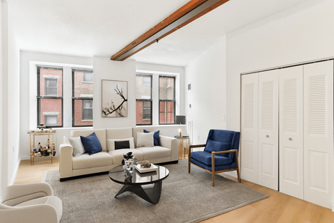 A living room with a white couch, a blue chair, and a coffee table.