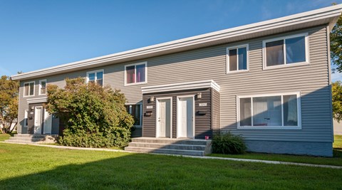 A grey house with a white door and windows.