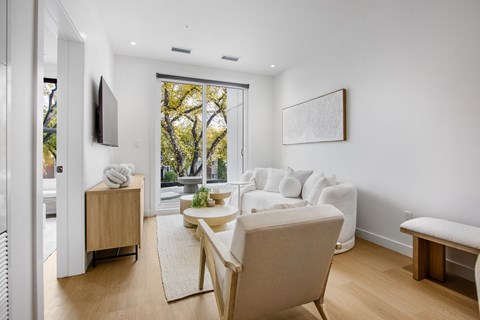 A living room with a white couch and a wooden chair.