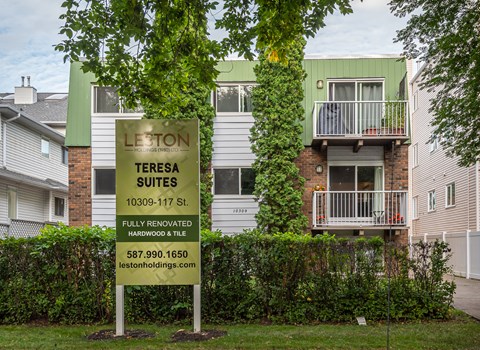A sign for Leston Teresa Suites is in front of a building.