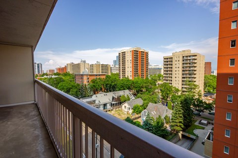 A balcony overlooks a residential area with houses and tall buildings.