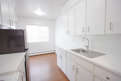 A kitchen with white cabinets and a black refrigerator.