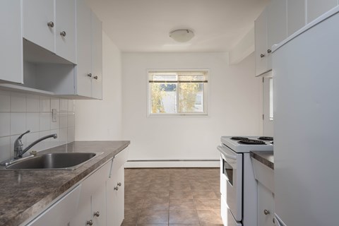 A kitchen with white cabinets and a window.