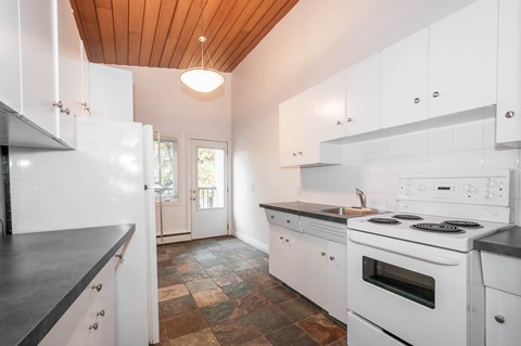 A modern kitchen with white cabinets and a wooden ceiling.