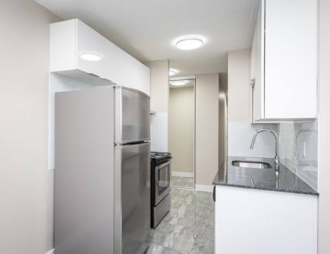 A kitchen with a refrigerator, oven, and sink.
