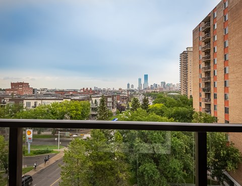 A view of a city from a balcony with a car on the road.