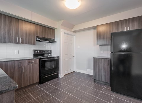 A kitchen with a black refrigerator, stove, and oven.
