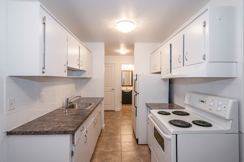 A kitchen with white cabinets and a white stove top oven.