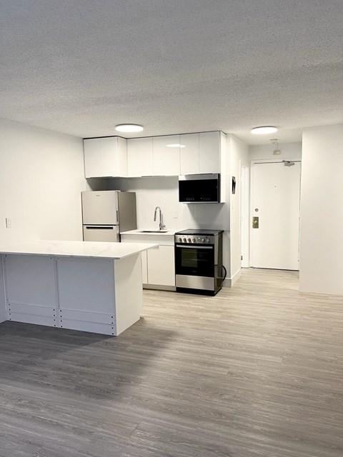 A modern kitchen with a white countertop and stainless steel appliances.