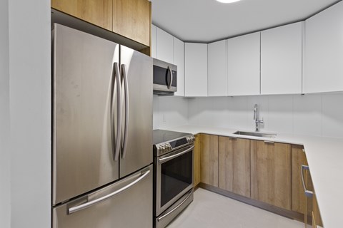 A modern kitchen with a stainless steel refrigerator and wooden cabinets.