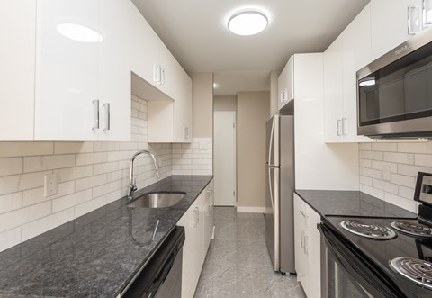 A kitchen with black countertops and white cabinets.