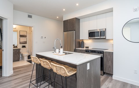 A modern kitchen with a white countertop and wooden cabinets.