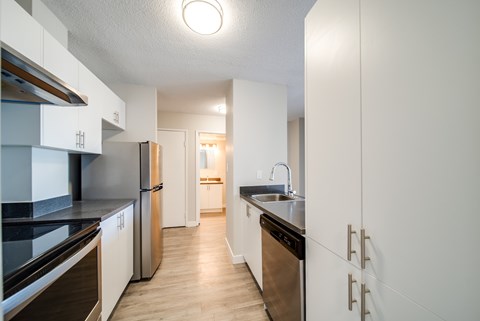 A kitchen with white cabinets and a black counter top.