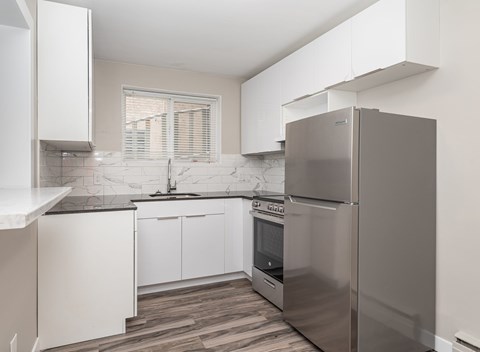 A modern kitchen with a stainless steel refrigerator and white cabinets.