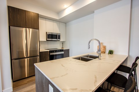 A kitchen with a stainless steel refrigerator and a white countertop.