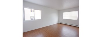 Empty room with wooden floor and two windows.